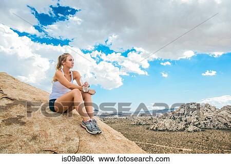 Stock Image - Woman taking break on mountain, Joshua Tree National Park, California, US. Fotosearch
