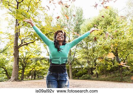 Woman throwing autumn leaves into air View Large Photo Image Stock Photo - Woman throwing autumn leaves into air. Fotosearch