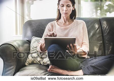 Woman using digital tablet on sofa View Large Photo Image Stock Photograph - Woman using digital tablet on sofa. Fotosearch