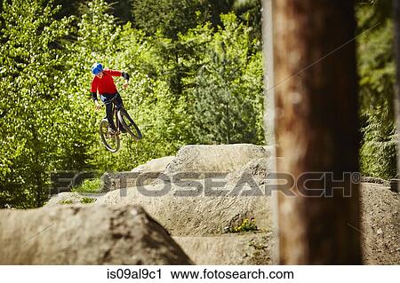 Young female bmx biker jumping mid air from rocks in forest View Large Photo Image Stock Image - Young female bmx biker jumping mid air from rocks in forest. Fotosearch