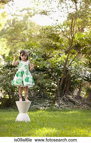 Young girl in garden, standing on pedestal View Large Photo Image Stock Image - Young girl in garden, standing on pedestal. Fotosearch