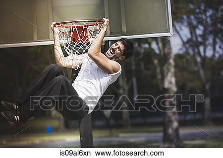 Young male basketball hanging from basketball hoop View Large Photo Image Picture - Young male basketball hanging from basketball hoop. Fotosearch