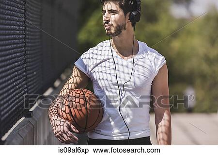 Young male basketball player walking over footbridge listening to headphones View Large Photo Image Stock Photography - Young male basketball player walking over footbridge listening to headphones. Fotosearch