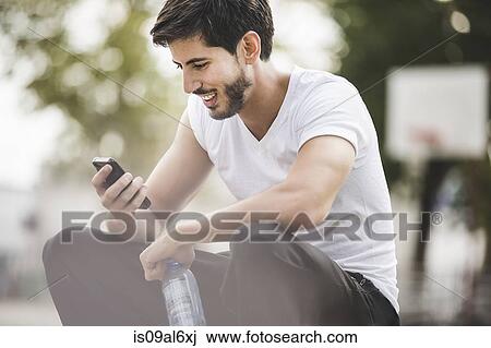 Young male basketball reading texts on smartphone View Large Photo Image Stock Image - Young male basketball reading texts on smartphone. Fotosearch