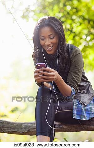 Young woman using smartphone on park bench View Large Photo Image Stock Image - Young woman using smartphone on park bench. Fotosearch