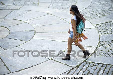 Stock Photography - Young woman walking on paving slabs, high angle. Fotosearch
