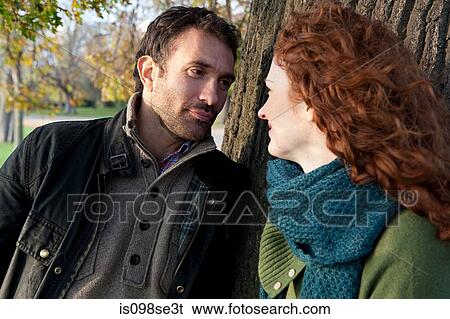 Stock Photograph - A couple face to face next to a tree. Fotosearch