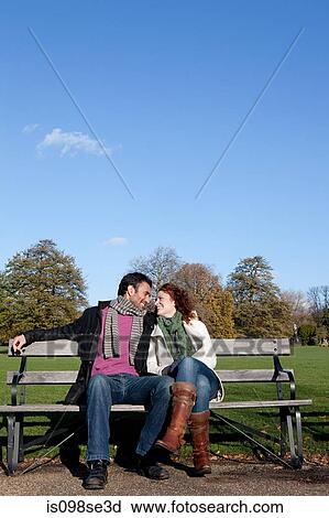 A couple face to face sitting on a park bench View Large Photo Image Stock Image - A couple face to face sitting on a park bench. Fotosearch