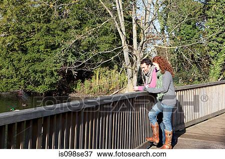 A couple look out over the water from a bridge View Large Photo Image Stock Photo - A couple look out over the water from a bridge. Fotosearch