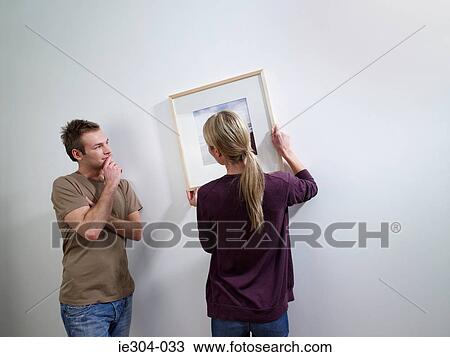 Stock Image - A couple putting art on a wall. Fotosearch