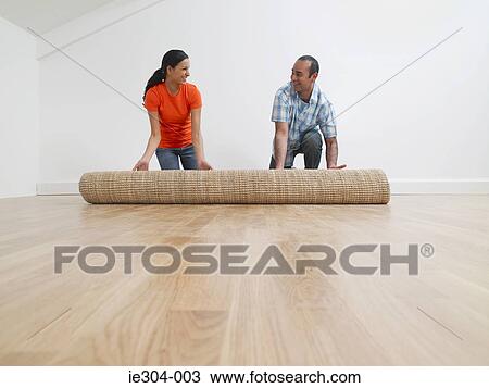 Stock Image - A couple rolling out a rug. Fotosearch