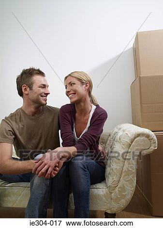A couple sat on a sofa in their new home View Large Photo Image Stock Photo - A couple sat on a sofa in their new home. Fotosearch