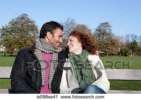 Stock Image - A couple sitting face to face on a park bench. Fotosearch