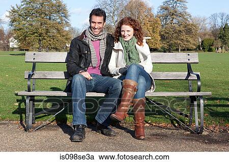 Stock Image - A couple sitting on a park bench. Fotosearch
