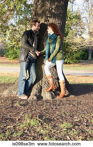 Picture - A couple stand face to face next to a tree. Fotosearch
