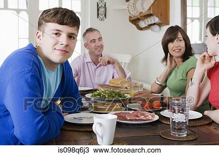 A family sat at a dining table View Large Photo Image Stock Image - A family sat at a dining table. Fotosearch
