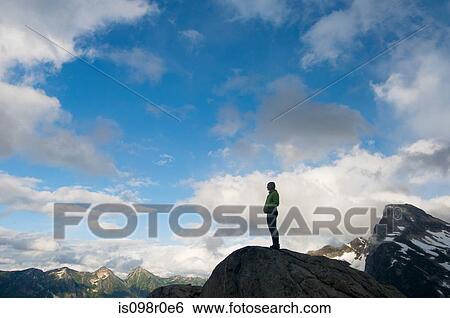 Stock Photograph - A female climber standing on a rock. Fotosearch