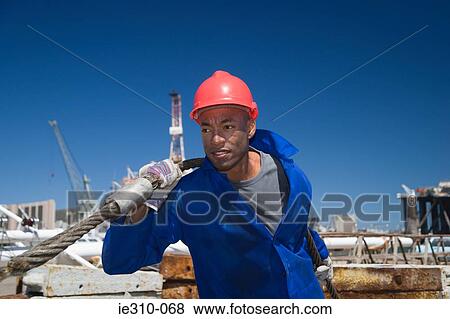 Stock Photo - A harbour worker pulling a rope. Fotosearch