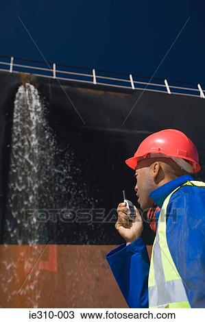A harbour worker using a walkie talkie View Large Photo Image Stock Image - A harbour worker using a walkie talkie. Fotosearch