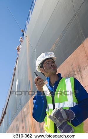 A harbour worker using a walkie talkie View Large Photo Image Stock Image - A harbour worker using a walkie talkie. Fotosearch