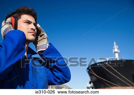 A harbour worker wearing ear defenders View Large Photo Image Stock Photograph - A harbour worker wearing ear defenders. Fotosearch