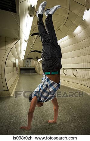 Stock Image - A man doing a handstand on the underground. Fotosearch