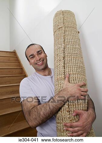 A man holding a rug in his new home View Large Photo Image Stock Image - A man holding a rug in his new home. Fotosearch