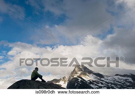 Stock Image - A woman sat on a mountain. Fotosearch