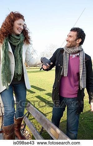 A woman walking on a park bench whilst holding hands with her partner View Large Photo Image Stock Image - A woman walking on a park bench whilst holding hands with her partner. Fotosearch