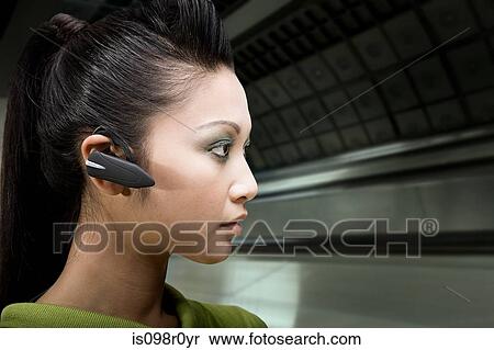 A woman wearing a bluetooth headset View Large Photo Image Stock Photography - A woman wearing a bluetooth headset. Fotosearch