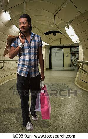 Picture - A young man carrying shopping bags. Fotosearch