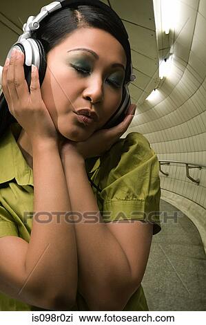 A young woman listening to music View Large Photo Image Stock Image - A young woman listening to music. Fotosearch