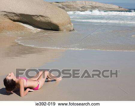Stock Photo - A young woman reclining on a beach. Fotosearch