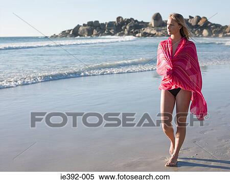 Stock Photography - A young woman walking along a beach. Fotosearch