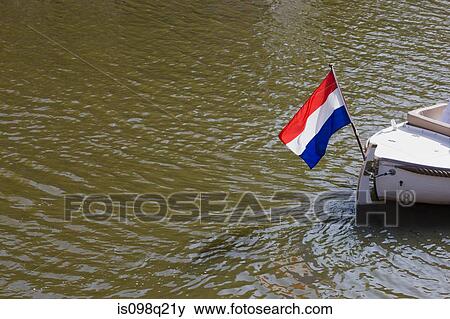 Boat on canal with dutch flag View Large Photo Image Stock Photo - Boat on canal with dutch flag. Fotosearch