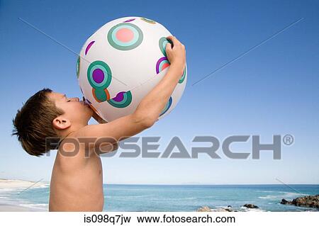 Boy blowing up beach ball View Large Photo Image Stock Photo - Boy blowing up beach ball. Fotosearch