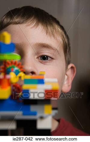 Stock Image - Boy looking over plastic blocks. Fotosearch