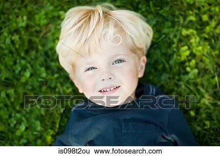 Stock Photograph - Boy lying on grass. Fotosearch