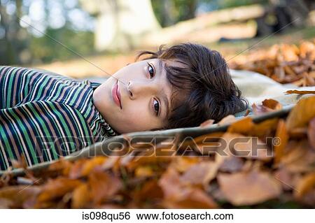 Boy lying on leaves View Large Photo Image Stock Photograph - Boy lying on leaves. Fotosearch