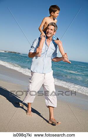 Stock Image - Boy on fathers shoulders by the sea. Fotosearch