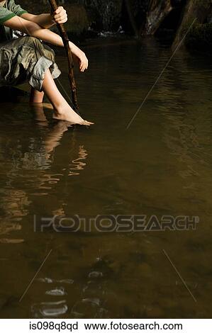 Stock Image - Boy with feet in river. Fotosearch