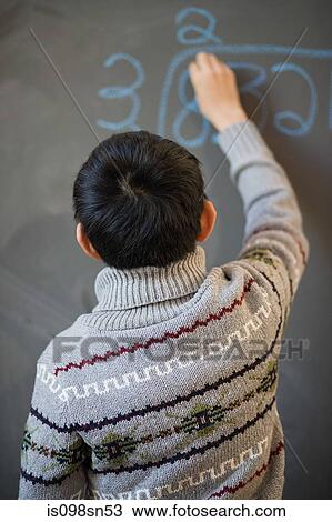 Stock Image - Boy writing on blackboard. Fotosearch