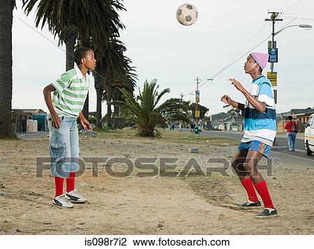 Stock Image - Boys playing football in street. Fotosearch