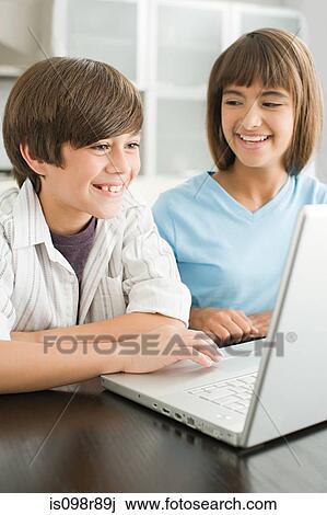 Brother and sister using a laptop computer View Large Photo Image Stock Image - Brother and sister using a laptop computer. Fotosearch