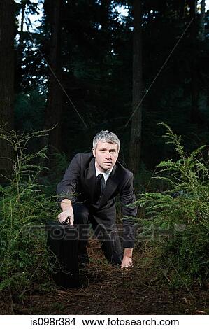 Picture - Businessman in forest holding briefcase. Fotosearch