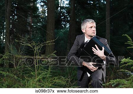 Businessman in forest holding briefcase View Large Photo Image Stock Photo - Businessman in forest holding briefcase. Fotosearch