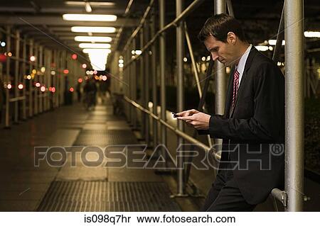 Businessman text messaging in a walkway View Large Photo Image Stock Photography - Businessman text messaging in a walkway. Fotosearch