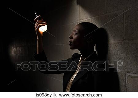 Stock Image - Businesswoman holding lightbulb. Fotosearch