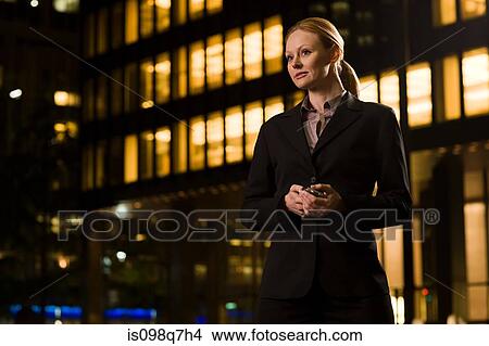 Picture - Businesswoman outside an illuminated building. Fotosearch