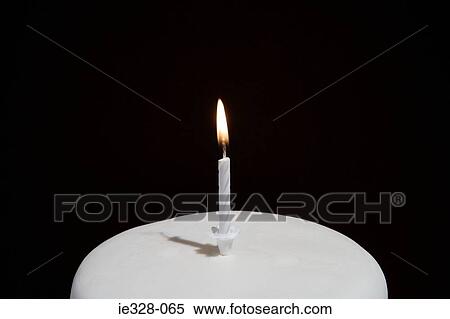 Stock Photography - Candle on a birthday cake. Fotosearch